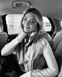 a black and white photo of a woman sitting in the back seat of a car