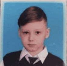 a young boy is wearing a vest and tie and looking at the camera .