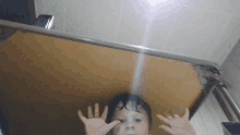 a young boy making a funny face with his hands in front of a mirror