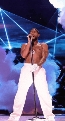 a shirtless man is singing into a microphone on a stage .