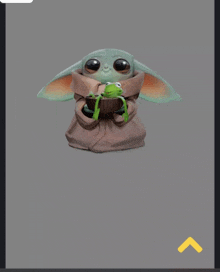 a baby yoda is holding a green frog in its hands