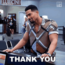 a man in a plaid shirt stands in front of a desk with the words thank you written on it