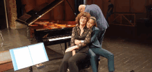 a group of people posing in front of a piano with a sheet music stand in the foreground