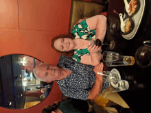 a man and a woman are sitting at a table with glasses of wine