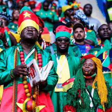 a group of people wearing colorful costumes and hats with one man holding a book that says ' ghana ' on it