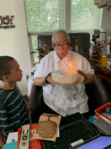 an elderly man blows out a candle on a cake