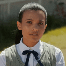 a close up of a girl wearing a sweater vest and a white shirt with netflix written on the bottom