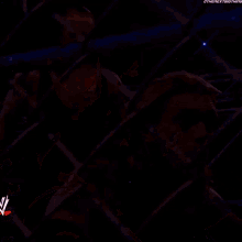 the undertaker and edge are behind a chain link fence during a wrestling match .