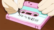 a person is writing on a cassette tape with a marker .