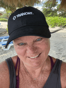 a woman wearing a black tranont hat smiles for the camera