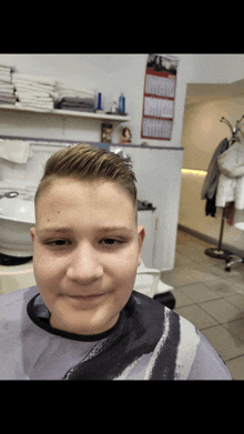 a boy in a barber shop with a calendar on the wall behind him