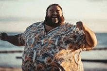 a very fat man with a beard is standing on the beach .