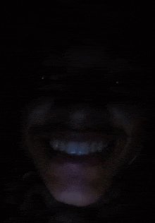 a close up of a woman 's face smiling in the dark