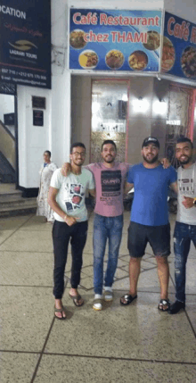 a group of young men pose in front of a cafe restaurant