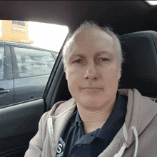 a man sitting in a car with a store sign in the background