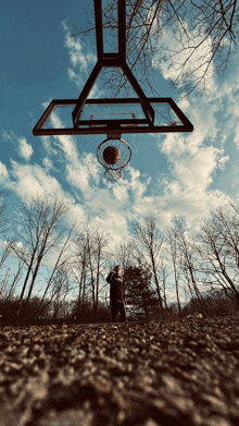 a basketball going through a hoop with a person standing in the background