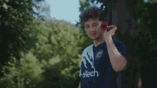 two young men are standing next to each other in a park . one of the men is wearing a blue and white jersey .