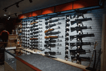 a brick wall with a lot of guns hanging on it in a store