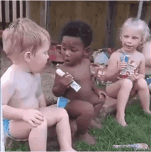 a group of children sitting on the grass eating ice cream