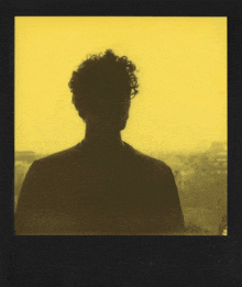 a silhouette of a man with curly hair is against a yellow background