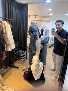 a man is taking a picture of a woman in a dress in front of a mirror