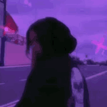 a woman is standing in front of a purple sky .