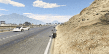 a man riding a motorcycle on the side of a road with a car in the background