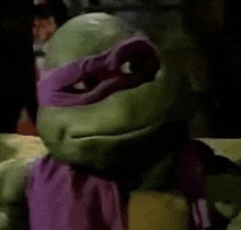 a close up of a teenage mutant ninja turtle wearing a purple scarf and mask .