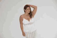 a woman in a white dress with a striped top is standing in front of a white wall