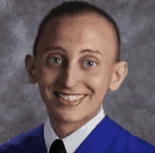 a young man in a blue graduation cap and gown is smiling for the camera .