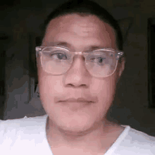 a man wearing glasses and a white shirt is making a face .