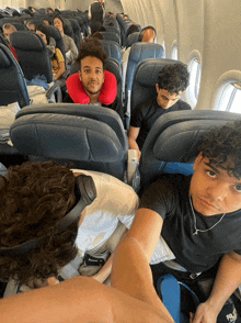 a group of people sitting on an airplane with one wearing headphones