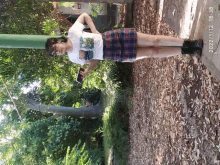 a girl wearing a plaid skirt and a t-shirt with a picture of a frog on it