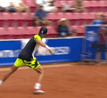 a man in a black shirt and yellow shorts is running on a tennis court in front of a sign that says ' toyota '