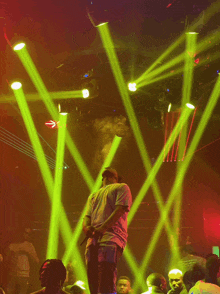 a man singing into a microphone in front of a crowd with green lights