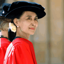 a woman wearing a red gown and a black hat