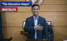 a man in a suit stands in front of a podium with the words " the education mayor " written above him