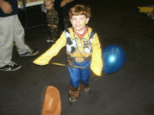 a little boy dressed as woody from toy story holds a blue balloon