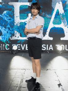 a young man stands in front of a sign that says hic eve sia tou