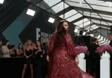 a woman in a red dress is dancing on a red carpet in front of a crowd of people .