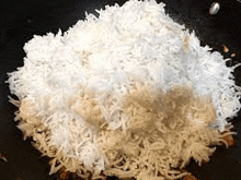 a pile of rice is being cooked in a frying pan .