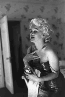 a black and white photo of a woman holding a bottle of chanel perfume