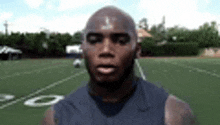 a man is standing on a football field with his eyes closed and looking at the camera .