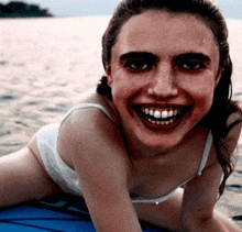 a woman in a bikini smiles while laying on a surfboard