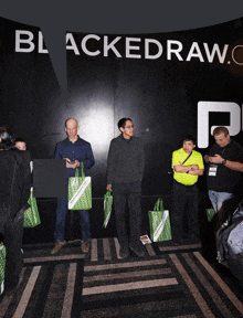 a group of people standing in front of a sign that says blackedraw.com