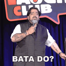 a man is holding a microphone in front of a sign that says " bata do "