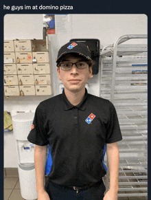 a man wearing a domino 's shirt and hat stands in a kitchen