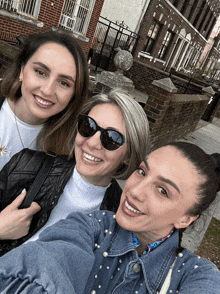 three women are posing for a picture and one of them is wearing sunglasses