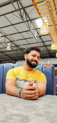 a man wearing a yellow surface shirt is sitting at a table