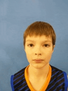 a young boy is wearing a blue and orange striped shirt .